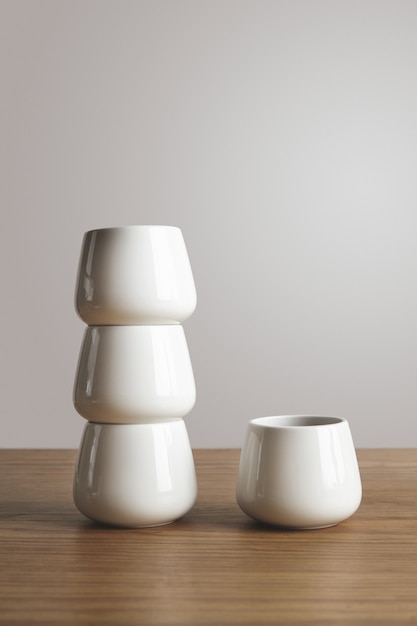 Vista lateral superior em forma de xícaras de café simples brancas em formato piramidal em mesa grossa de madeira isolada