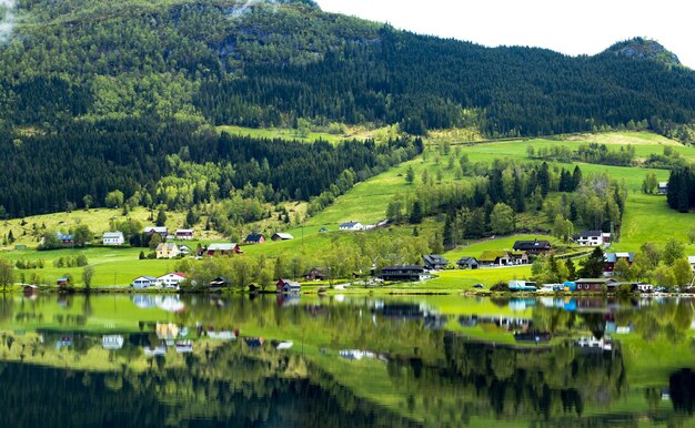 Vista panorâmica de casas refletindo em um lago calmo perto de uma montanha na Noruega