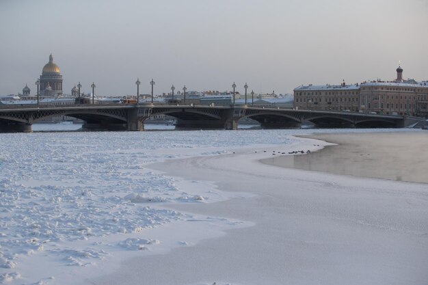 Vista panorâmica de inverno de são petersburgo no dia gelado, a catedral de isaac e a ponte blagoveshenskiy no fundo, vapor sobre o rio neva congelado, edifício do almirantado