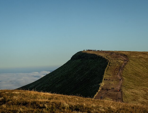 Vista panorâmica de pessoas caminhando em direção ao penhasco de uma montanha