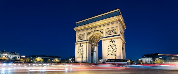 Vista panorâmica do Arco do Triunfo à noite com as luzes dos carros