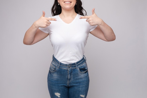 Foto grátis vista recortada da morena em pé na camisa branca e calça jeans