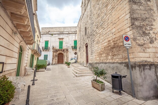 Vista sedutora das ruas vazias da cidade velha de Martina Franca com belas casas pintadas de branco entre vegetação. Dia maravilhoso em uma cidade turística, Puglia, Itália.