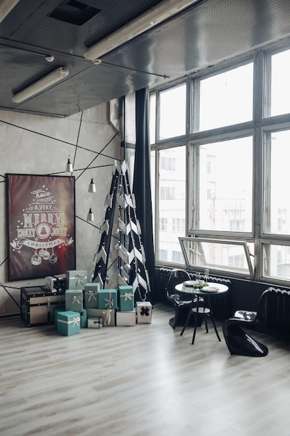 Vista sobre mesa redonda lindamente decorada com ramo de abeto natural, vela, duas taças, pratos contra sofá clássico em apartamento moderno.