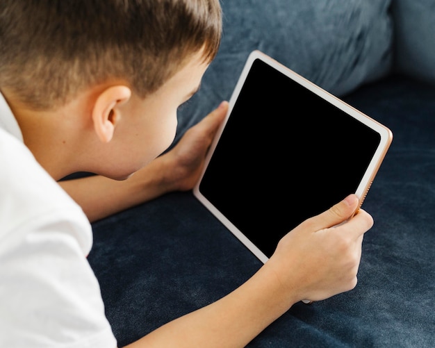 Vista sobre o ombro da criança segurando um tablet digital
