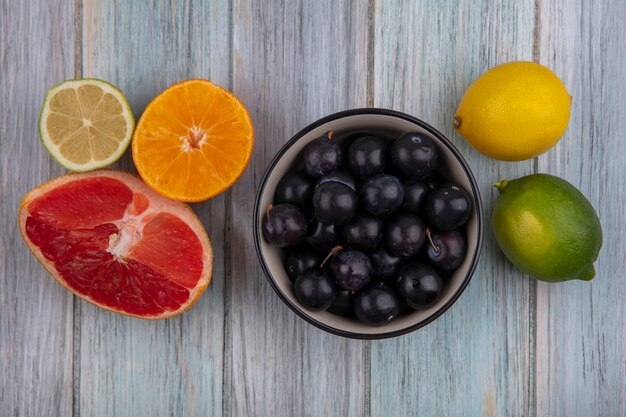 Vista superior ameixa cereja em uma tigela com grapefruit rodelas de laranja, limão e lima em fundo cinza