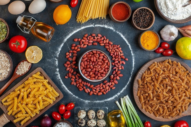 Foto grátis vista superior amendoins frescos em círculo em torno de ovos vegetais massas e temperos em fundo escuro cor alimentos crus refeição foto saúde dieta