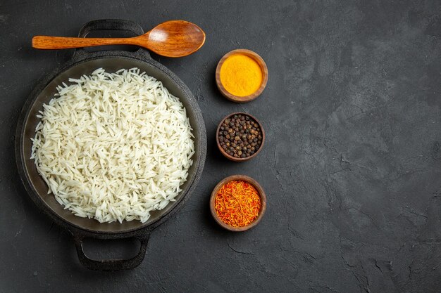 Vista superior arroz cozido dentro da panela com temperos na superfície escura refeição comida arroz jantar oriental