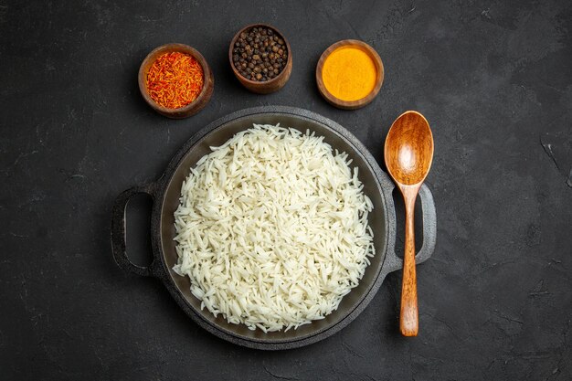 Vista superior arroz cozido dentro da panela com temperos na superfície escura refeição comida arroz jantar oriental