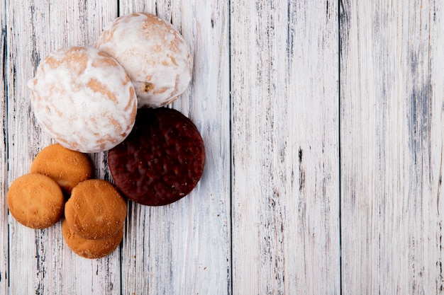 Vista superior biscoitos de baunilha doces biscoitos de chocolate e pão de gengibre à esquerda, com espaço de cópia no fundo branco de madeira