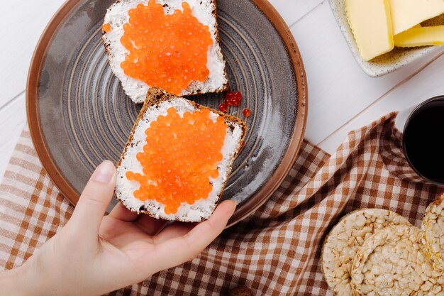 Vista superior caviar vermelho pão de centeio torrada com queijo cottage caviar vermelho manteiga estaladiça crocante e copo de suco de cereja em cima da mesa