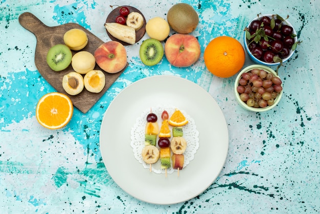 Vista superior composição de frutas fatiadas e inteiras no fundo azul biscoito exótico de frutas