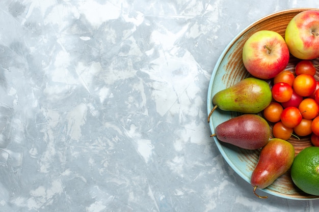 Vista superior composição de frutas maçãs peras tangerinas e ameixas na mesa branca clara.