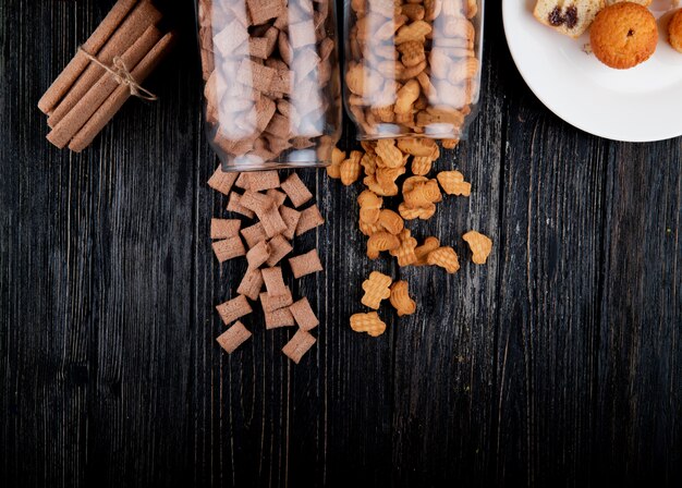 Vista superior cópia espaço cookies em um pote de flocos de milho e palitos de milho em um fundo preto de madeira