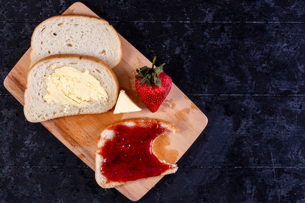 vista superior cópia espaço fatias de pão e manteiga com uma fatia de pão com geléia a bordo com morangos