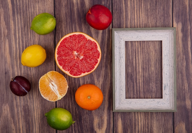 Vista superior cópia espaço moldura cinza com laranja limão limão e meia toranja em fundo de madeira