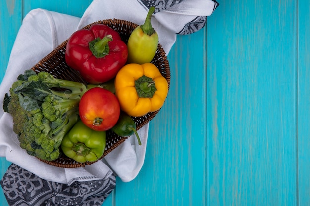 Foto grátis vista superior cópia espaço tomate com pepino e pimentão com brócolis em uma cesta em uma toalha de cozinha em um fundo turquesa