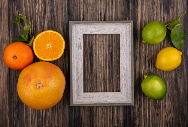 Vista superior cópia espaço toranja com laranja limão limão e moldura cinza em fundo de madeira