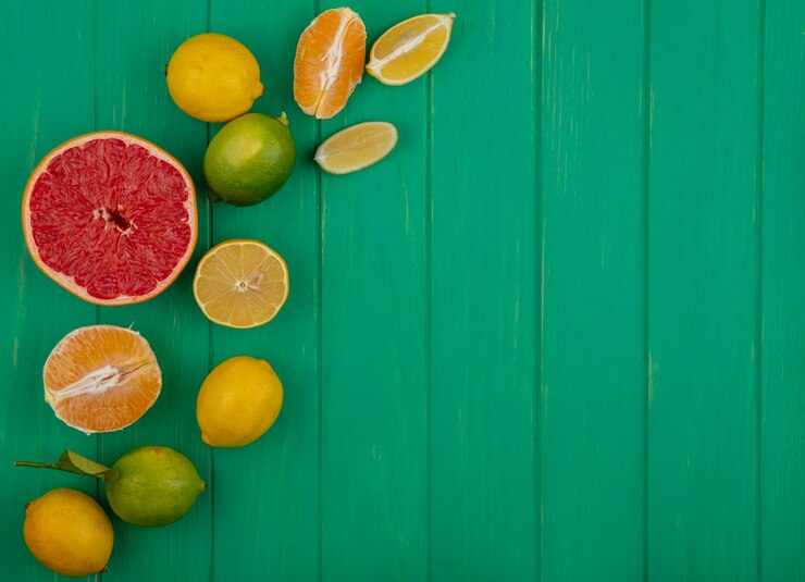 Foto grátis vista superior copie o espaço meia toranja com laranjas descascadas e fatias de limão sobre um fundo verde