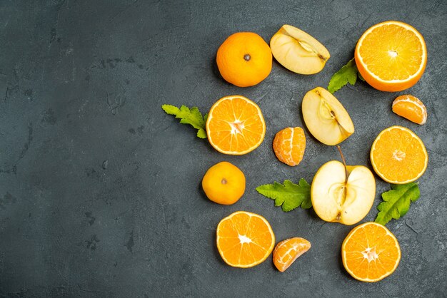 Vista superior corte laranjas e maçãs em superfície escura