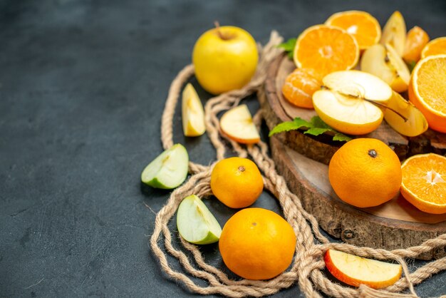 Vista superior corte maçãs e laranjas na placa de madeira coquetel em fundo escuro