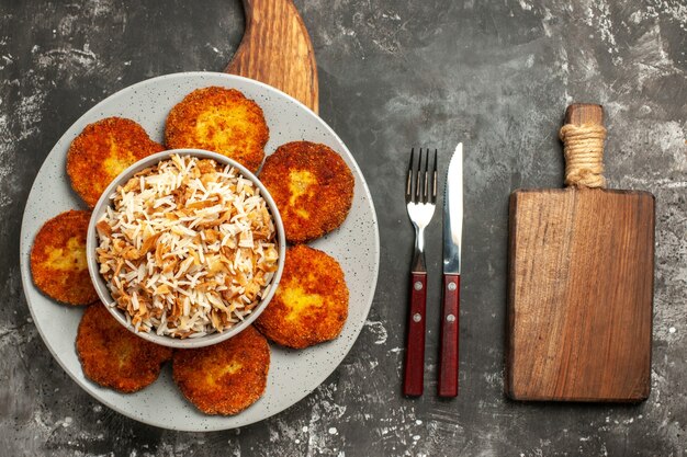 Vista superior costeletas fritas com arroz cozido em um prato de rissole de carne de superfície escura