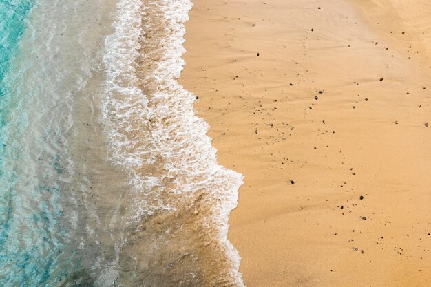 Vista superior da água do mar, tocando a areia na costa