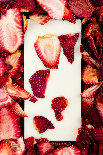 Foto grátis vista superior da barra de chocolate branca sobre fundo de fatias de morango secas