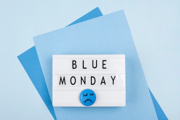 Vista superior da caixa de luz azul de segunda-feira com rosto triste e papel