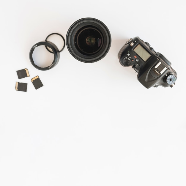 Vista superior da câmera dslr; cartões de memória e lente da câmera com anéis de extensão em pano de fundo branco