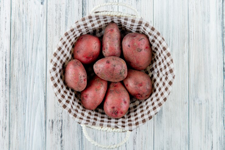 Foto grátis vista superior da cesta cheia de batatas em fundo de madeira com espaço de cópia