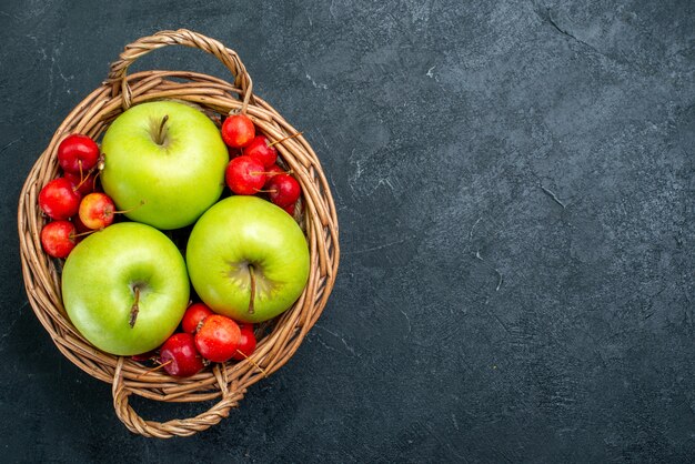 Vista superior da cesta com frutas, maçãs e cerejas no fundo escuro frutas composição da baga frescura planta