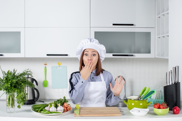 Vista superior da chef feminina chocada e legumes frescos na cozinha branca