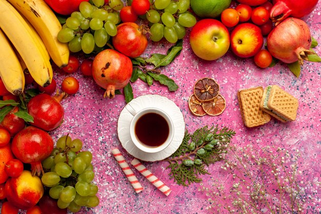 Vista superior da composição de frutas frescas frutas coloridas com waffles e xícara de chá na superfície rosa