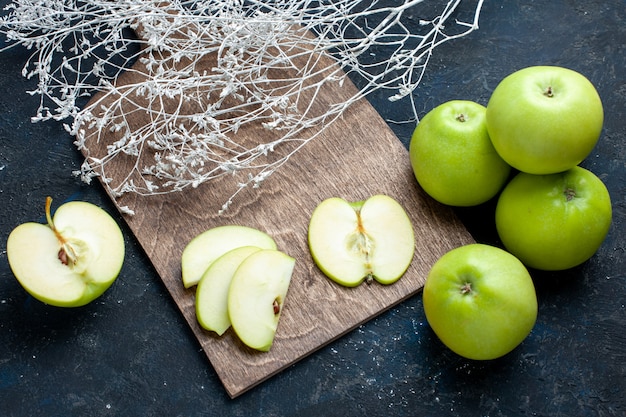 Vista superior da composição de maçãs verdes frescas com metade do corte fatiado e alinhado no escuro, frutas frescas maduras