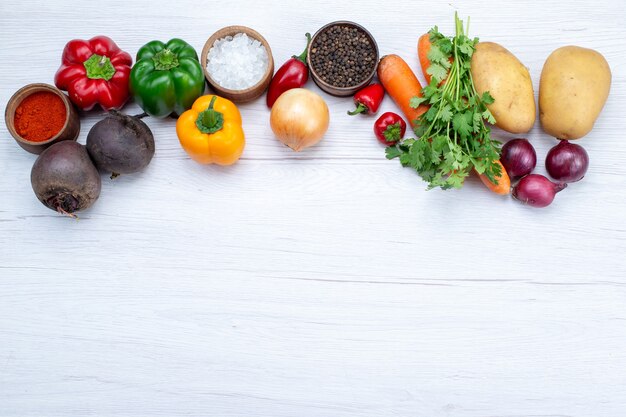 Vista superior da composição de vegetais com vegetais frescos, verdes, feijões crus, cenouras e batatas, à luz de fundo, refeição alimentar