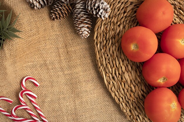 Vista superior da configuração da mesa de Natal com tomates, bengalas e pinhas