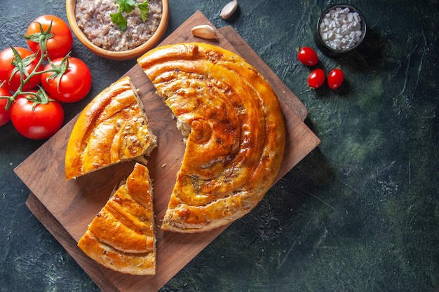 Vista superior da deliciosa torta de carne com tomate vermelho na superfície escura