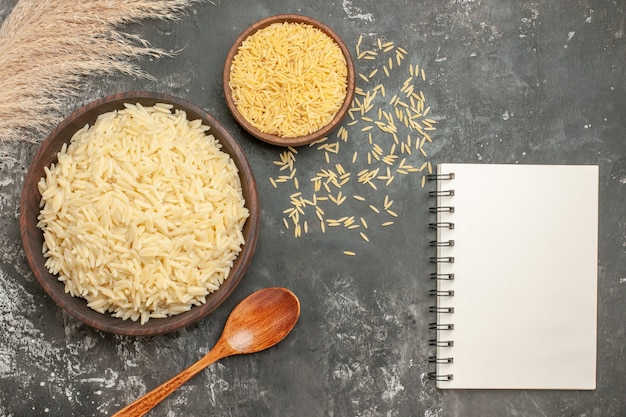 Foto grátis vista superior da farinha de arroz e arroz cru com uma colher ao lado do caderno