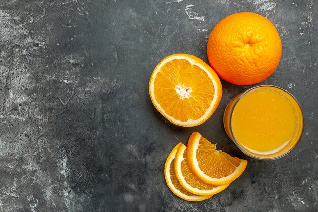 Vista superior da fonte de vitamina cortada, laranjas frescas inteiras e inteiras e suco em fundo cinza