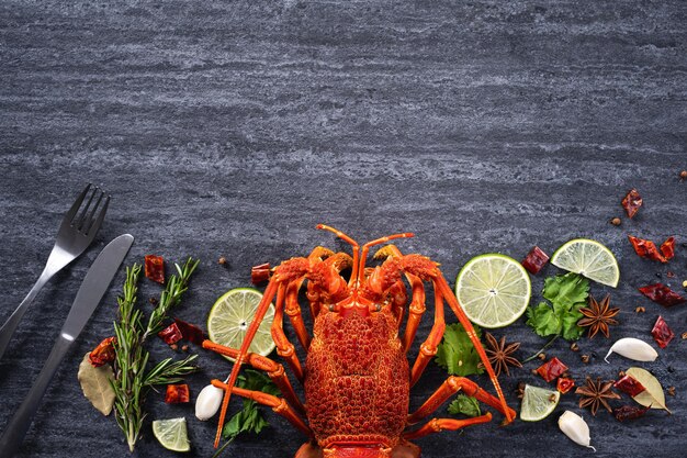 Vista superior da lagosta cozida cozida, deliciosa refeição de frutos do mar jantar com faca e garfo em fundo de ardósia de pedra preta para o conceito de dia dos namorados.