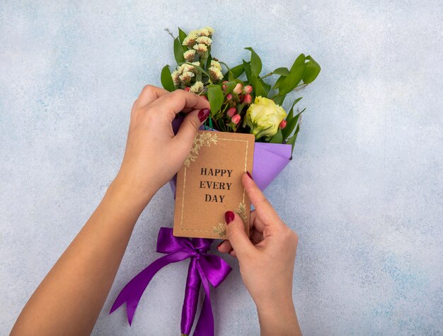 Foto grátis vista superior da mão feminina segurando um buquê de rosa com folhas e frutos rosa em branco