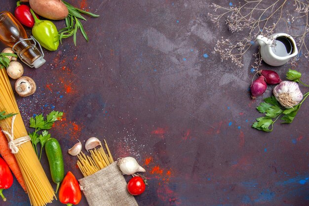 Vista superior da massa crua com vegetais frescos em comida de salada à superfície escura