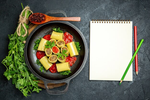 Vista superior da massa italiana com molho de tomate verde e carne dentro de uma panela em um espaço cinza escuro