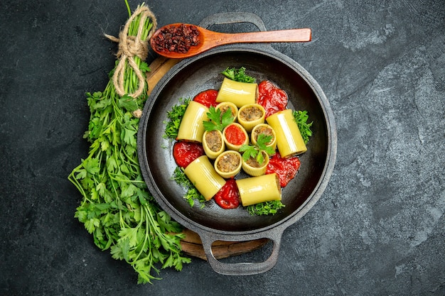 Vista superior da massa italiana com molho de tomate verde e carne dentro de uma panela no espaço cinza