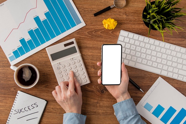 Vista superior da mesa de escritório com gráfico de crescimento e mãos usando calculadora