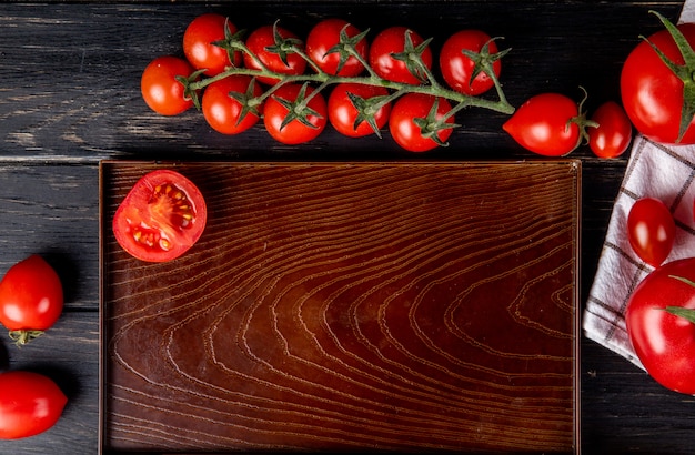 Vista superior da metade cortada tomate na bandeja e os inteiros na superfície de madeira