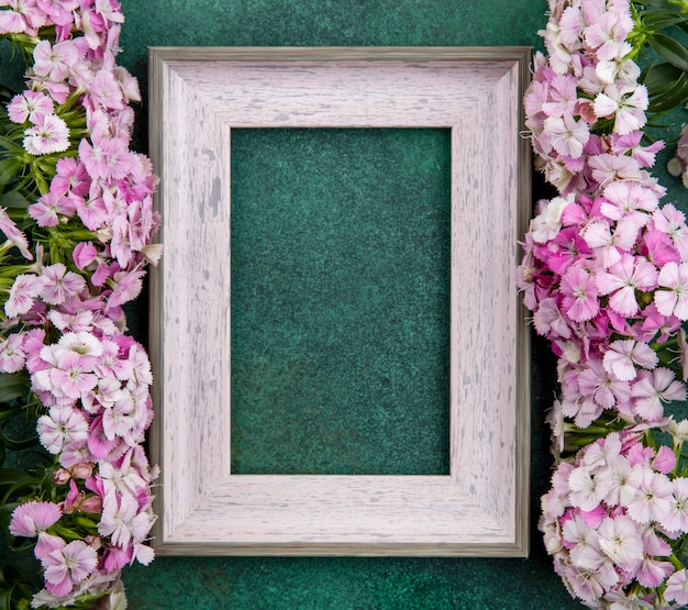 Vista superior da moldura cinza com flores roxas claras em uma superfície verde