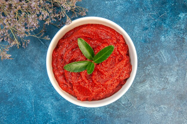 Vista superior da pasta de tomate fresco na mesa azul