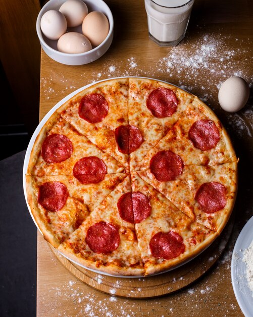 Vista superior da pizza de salame com queijo e calabresa em uma mesa de madeira